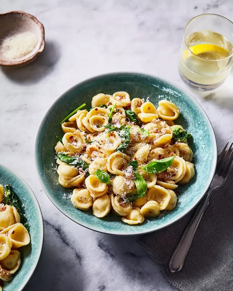 One Pan Orecchiette Pasta 3 A person stirring a bubbling one-pan orecchiette pasta dish in a large skillet, with steam rising, indicating the cooking process is underway.